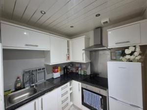 a kitchen with white cabinets and a sink and a refrigerator at Cosy and Bright 3-bedroom flat in Glasgow