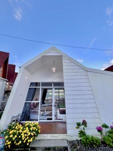 a white house with a window and some flowers at Glamping Calla in Banjarnegara +2 photos