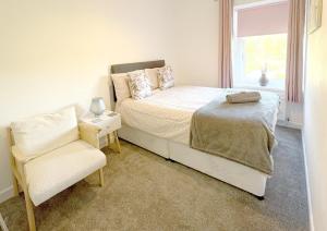 a bedroom with a bed and a chair and a window at Pleasant View Cottage in Trehafod