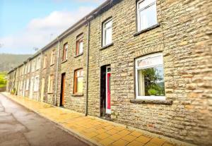 a brick building with a red door on a street at Pleasant View Cottage in Trehafod