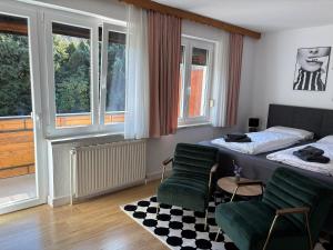 a bedroom with a bed and a chair and windows at Pension Kitty in Pörtschach am Wörthersee
