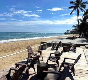 a row of chairs on a beach with the ocean at Panoramic Views Two Decks 1st Row Ocean Kite Beach in Cabarete