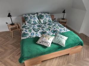 a bed with a green blanket and pillows on it at Bukowy Zakątek in Brenna