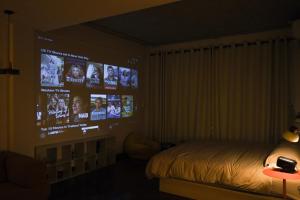 a bedroom with a bed and a bunch of tv screens at Arunne in Bangkok Yai