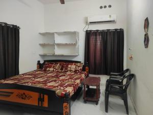 a bedroom with a bed and a chair at SRI PADMAVATHI NiVAS in Pithāpuram