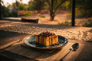 a piece of cake on a plate on a table at Dheer- BnB at an Artist's Abode in Shānti Niketan