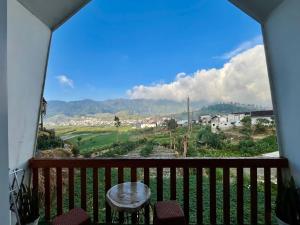 a balcony with a table and a view of the mountains at Glamping Calla in Banjarnegara