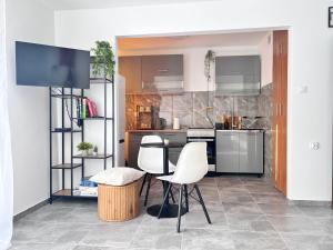 a kitchen with white chairs and a tv in it at Sunset Studio in Kwidzyn