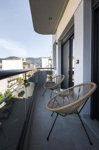 a balcony with two chairs and a view of a city at Antheon Suites Volos in Volos