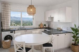 a white kitchen with a white table and a window at Two BR Sea View with Balcony and Pool Paphos in Khlorakas