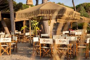 a group of tables and chairs with umbrellas at NOMAD ARGENTARIO - Area Sosta Camper - NO TENDE - NO CARAVAN - Empty Pitch Only Campervan RV - SOLO PIAZZOLA PER IL PROPRIO CAMPER - Tariffa fino a 4 persone - TUTTI I SERVIZI INCLUSI in Albinia