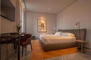 a hotel room with a bed and a desk and a table at The Bank Hotel - Etruria Collection in Perugia