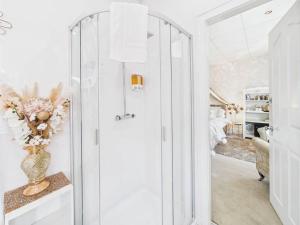 a bathroom with a glass shower with a vase of flowers at Sorrento House in Blackpool +56 photos
