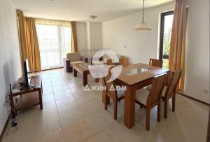 a living room with a dining room table and a television at Dimi's Bay View Villas in Kosharitsa