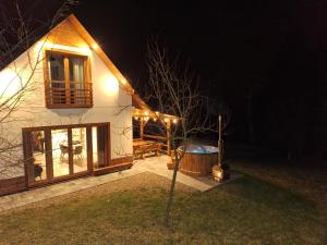 a house at night with lights on the side of it at Leśna Chata domek z balią in Sękowa
