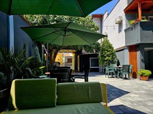 eine Terrasse mit einer grünen Couch und einem Sonnenschirm in der Unterkunft Hotel Ari in Prizren