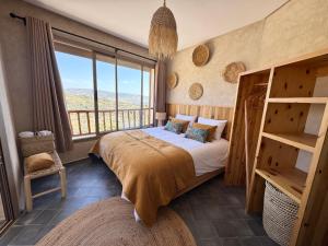 a bedroom with a bed and a large window at Manapany Surf Camp in Tamraght Ouzdar