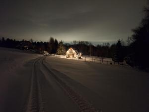 a house on a snow covered road in front of a house at Leśna Chata domek z balią in Sękowa