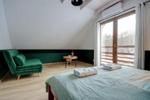 a bedroom with a bed and a green chair at Leśna Chata domek z balią in Sękowa