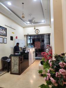 a man sitting at a counter in a room with flowers at New Mewar Darshan in Udaipur