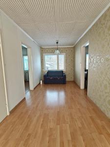 an empty living room with a couch and wood floors at Simple Cozy House in Raahe