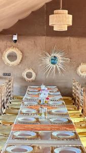 a long table with chairs and plates on it at Stellar Luxury Camp in Merzouga +46 photos