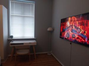 a room with a desk and a tv on the wall at Greenbrook Blue TwinSuite in Aalborg +7 photos