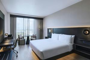 a hotel room with a large white bed and a desk at AC Hotel by Marriott Georgetown Guyana in Georgetown +28 photos