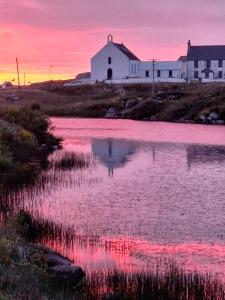 a church with a reflection in the water at sunset at Hillview in Daliburgh