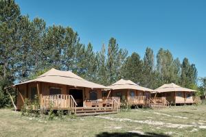 a row of tents in a field with trees at Les Maisons De Chante Oiseau, Maisons, Lodges, Tentes et Cabane in Sigonce