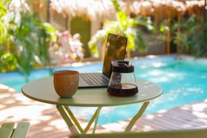 a table with a laptop and a cup on it at Refugio Surf Lodge in Tamarindo