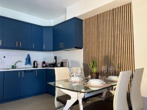 a kitchen with blue cabinets and a table with chairs at Aurora Luxury Apartment in Keramoti