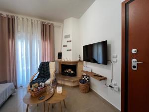 a living room with a fireplace and a tv on the wall at Aurora Luxury Apartment in Keramoti