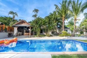 a swimming pool in front of a house with palm trees at NO 7 Garden Villa in Rawai Beach