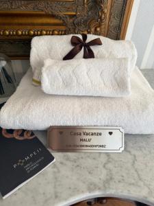 a stack of white towels with a sign on it at Casa Malù in Torre Annunziata