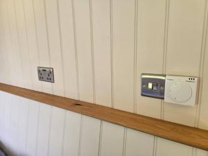 a wall with a lightswitch on a wall with a shelf at Trouble House in Tetbury