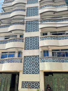 a man stands in front of a building with blue balconies at Skyview Bamburi Suites in Mombasa