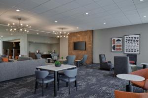 a waiting room with tables and chairs and a tv at Courtyard by Marriott Madison in Madison