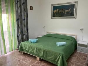 ein Schlafzimmer mit einem grünen Bett mit zwei Kissen darauf in der Unterkunft Bingo 2 in Alghero