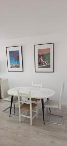 a white table and chairs in a room with paintings at Apartamento Marandel in Ronda