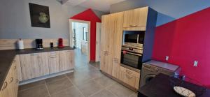 a kitchen with wooden cabinets and a red wall at Maison du Gué 2 chambres in Gurgy