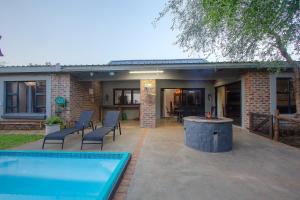 a patio with a pool and chairs and a house at White Sparrow Villa in Marloth Park
