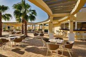 an outdoor patio with tables and chairs and palm trees at Sheraton Nouakchott Hotel in Nouakchott
