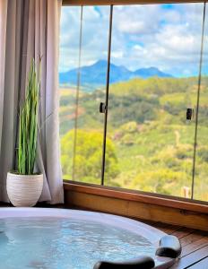 a hot tub in front of a window with a view at Chales Vidal in Venda Nova do Imigrante