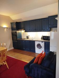 a kitchen with blue cabinets and a couch in a room at Aran View Loft in Knockfin Cross Roads