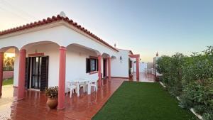 a white house with a table and chairs at Monte Rio House in Luz