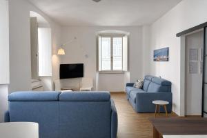 a living room with two blue couches and a tv at Bilocale in centro a 1 minuto da Piazza Unità in Trieste