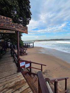 a sign on a beach with benches and the ocean at Ocean Rush in Zinkwazi Beach