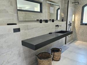 a bathroom with a sink and a mirror and two baskets at Suite Sieste en Provence in Entrecasteaux