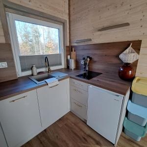 a kitchen in a tiny house with a sink and a window at Leśny Reset 2 in Grabowo